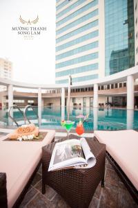 a balcony with a table with a drink and a book at Muong Thanh Luxury Song Lam Hotel in Vinh