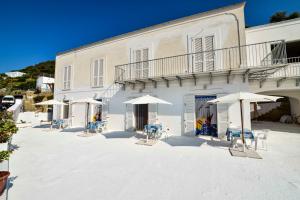 a white building with chairs and umbrellas in front of it at SoleMarePonza Casa Maria in Ponza
