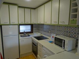 une cuisine avec des armoires blanches, un évier et un micro-ondes dans l'établissement Aldeas Taray Admer 14, à La Manga del Mar Meno