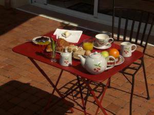 a red table with a tray of breakfast food on it at Chambres d'Hôtes Coteaux Sud in Jurançon