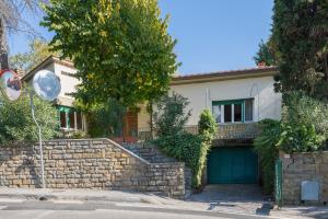a house with a stone wall and a blue garage at Casa con Giardino a 100 metri dal centro storico in Lucignano