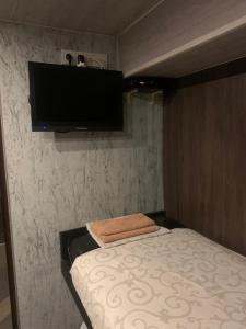 um pequeno quarto com uma cama e uma televisão de ecrã plano em Хостел ХАН em Kharkov