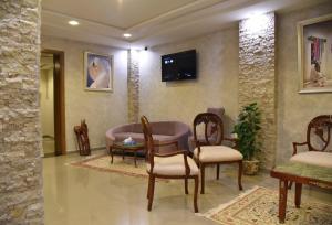 a living room with chairs and a tv on the wall at Larimar Hôtel Sfax in Sfax