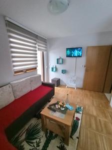 a living room with a red couch and a table at Apartment Gorski javor in Jahorina