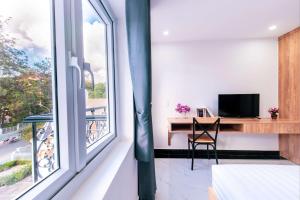 - une chambre avec un bureau et une grande fenêtre dans l'établissement Hoa Mi Condotel, à Đà Lạt