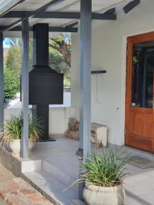 a front porch with a fireplace and a wooden door at Shepherd's Cottage in Nieu-Bethesda