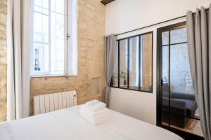 1 dormitorio con cama blanca y ventana en GemBnB Luxury Apartments - Residence Timbaud Paris-Oberkampf, en París