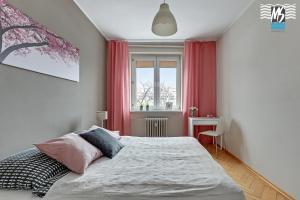 a bedroom with a bed with pink curtains and a window at MS Apartments Centrum Gdyni I in Gdynia