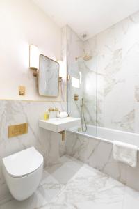 een witte badkamer met een toilet, een wastafel en een bad bij Brighton Brunswick Apartments in Brighton & Hove