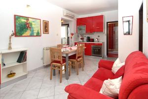 uma sala de estar com um sofá vermelho e uma mesa em Apartments Sunčica em Mali Lošinj