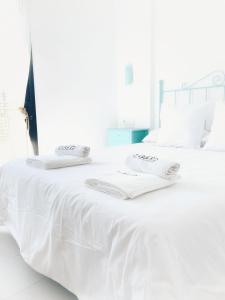 Una cama blanca con sábanas blancas y toallas. en 6 grifos habitaciones turísticas, en Barbate