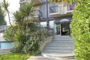 a building with stairs and palm trees in front of it at Hotel President in Cattolica