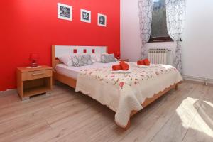 a bedroom with a bed and a red wall at Apartments Sunčica in Mali Lošinj