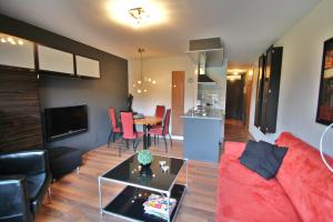 a living room with a red couch and a table at Heerlijk App APHRODITE - beg grond met TERRAS, eigen KEUKEN, Incl Verwarmd Hotel-ZWEMBAD, nabij Strand en Vuurtoren in Hollum