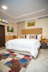 a bedroom with a large white bed and a rug at Brynx Haven - Cape Coast in Cape Coast