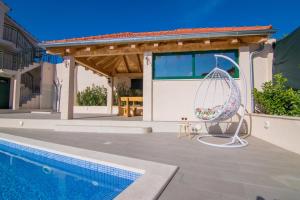 a house with a swimming pool and a patio at Villa Milena with heated pool and jacuzzi in Kostanje
