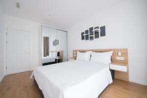 a white bedroom with a white bed and a mirror at Afthonia Apartamente Mamaia Nord in Mamaia Nord