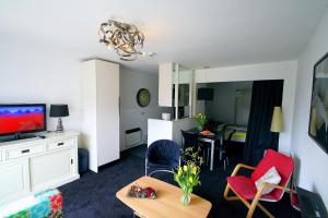 een woonkamer met een televisie en een kamer met een tafel bij Appartement ZEEDUIN, Beg grond, eigen Terras - volledige KEUKEN- Resort Amelander Kaap, Incl verwarmd Hotel-ZWEMBAD in Hollum