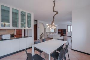 Casa Mary Tre - attico con terrazza a 2 passi dal lago في سيرمِيوني: مطبخ وغرفة طعام مع طاولة وكراسي بيضاء