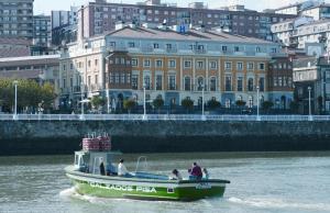 a small boat in the water in front of a building at Puente Colgante Boutique Hotel in Portugalete