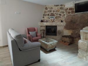 a living room with two chairs and a stone fireplace at La Lagareta de Olivia in Trevejo