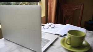 um computador portátil sentado numa mesa com uma chávena de café em Hotel El Farolito em Lima