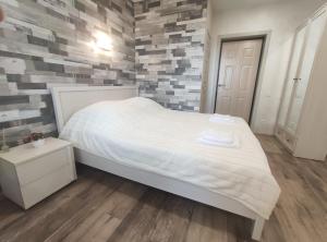 a bedroom with a white bed and a brick wall at Atmosfera - Студия в новом доме в центре города in Lipetsk