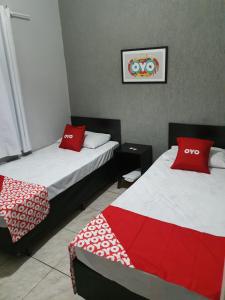 two beds in a room with red and white pillows at Hotel Mogi in Mogi das Cruzes