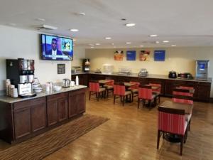 a restaurant with a bar with red chairs at Comfort Inn Cleveland Airport in Middleburg Heights