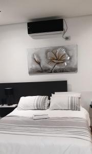 a bedroom with a white bed with a painting on the wall at Casa Mo Boutique Guest House in Bloemfontein