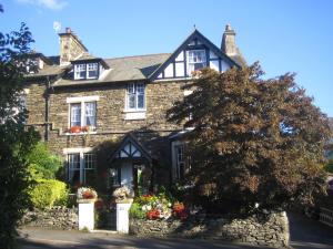 an old stone house with flowers in front of it at Denehurst Guest House - Adults Only in Windermere