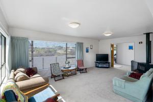 sala de estar con sofá, sillas y TV en Hit The Beach - Waitarere Beach Holiday Home, en Waitarere