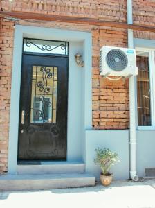 eine schwarze Tür in einem Backsteingebäude mit einem Lautsprecher in der Unterkunft Apartment Izabella in Tbilisi City