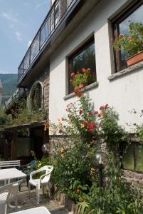 ein Gebäude mit einem Tisch, Stühlen und Blumen in der Unterkunft Hotel Ristorante Sassi Rossi in Taceno
