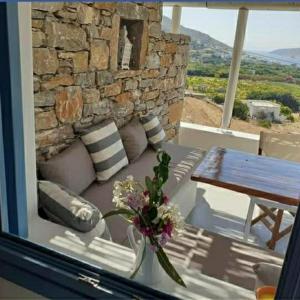 a couch sitting on a porch with a table and a stone wall at Kykladonisia Amorgos in Amorgos