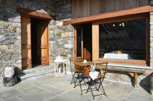 a patio with a table and chairs in front of a building at LA MURA’ - Il vostro posto nel Gran Paradiso in Ronco Canavese