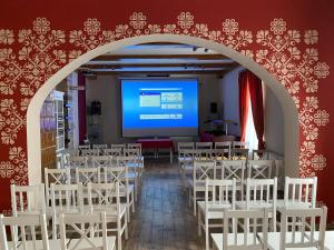 Habitación con sillas blancas y pantalla de proyección en Kamarás Klastrom House, en Mogyoród