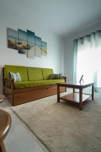 ein Wohnzimmer mit einem grünen Sofa und einem Couchtisch in der Unterkunft White Beach House in Praia da Areia Branca