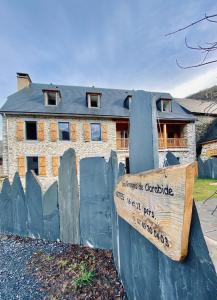 a house behind a fence with a sign in front at Les Granges de Clarabide in Loudenvielle