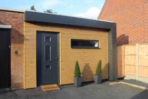 a garage with a black door and two plants at The Coneygree @ Northwick in Worcester