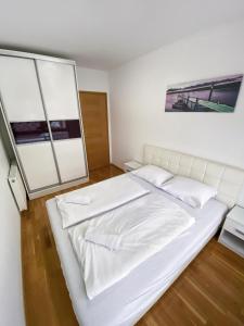 uma cama branca num quarto com duas janelas em Apartment Heaven em Sarajevo