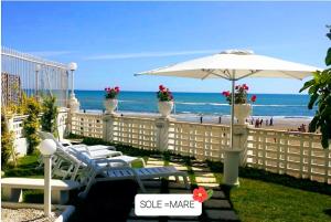 un patio con sedie e ombrellone e la spiaggia di Casa Genny a Nettuno