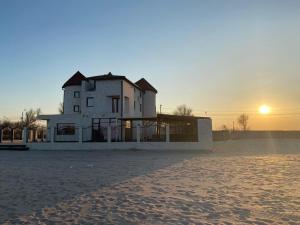 ein Haus am Strand mit Sonnenuntergang im Hintergrund in der Unterkunft Canada Castle in Eforie Nord