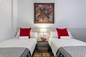 two beds with red pillows in a room at Zurriola Surf in San Sebastián