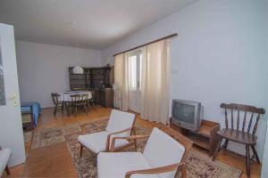 a living room with white chairs and a tv at Apartment in Veli Losinj 34684 in Veli Lošinj