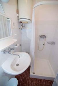 a white bathroom with a sink and a shower at Apartment in Veli Losinj 34684 in Veli Lošinj
