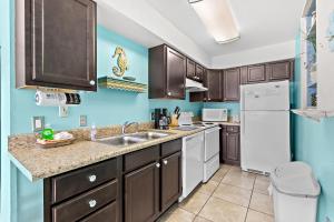 a kitchen with brown cabinets and a white refrigerator at Seas the Day in Navarre