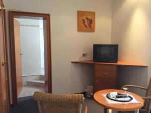 a room with a table and a television and a bathroom at Hotel-Pension Bergkranz in Braunlage