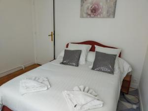 a white bed with two towels on top of it at Chatou Centre Ville in Chatou