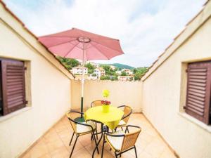 a yellow table with chairs and an umbrella on a balcony at Apartment in Vrbnik - Insel Krk 13622 in Vrbnik